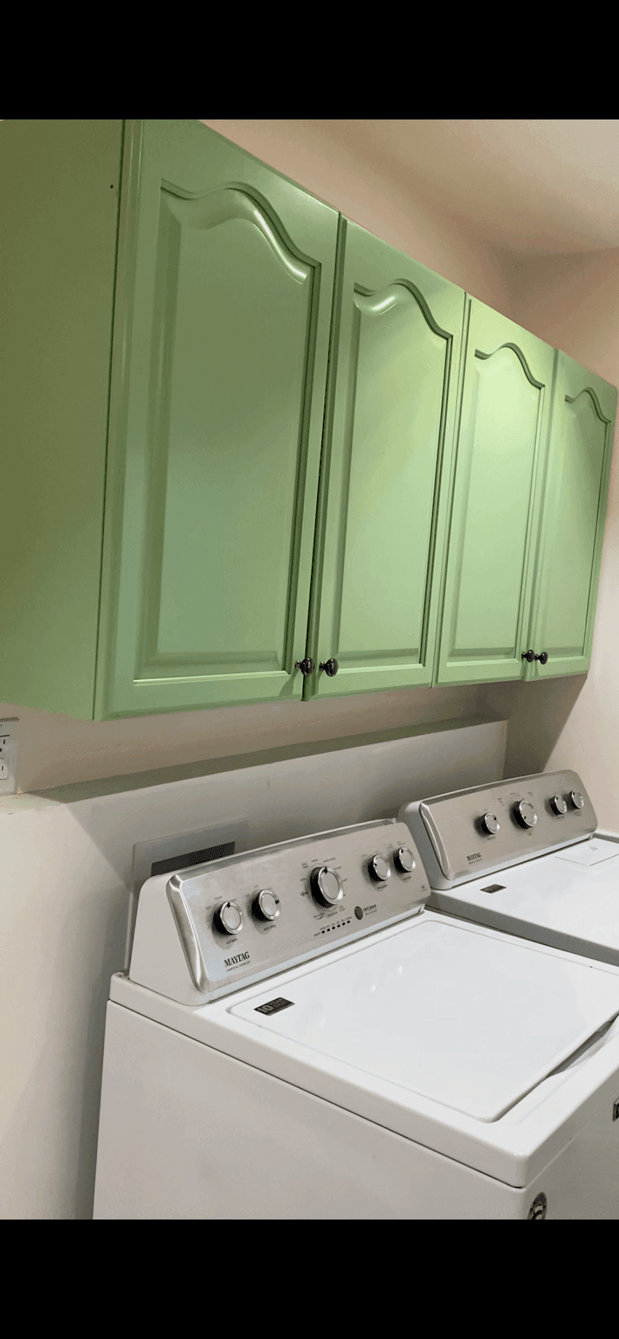 Laundry room with green cabinets and white washer and dryer.